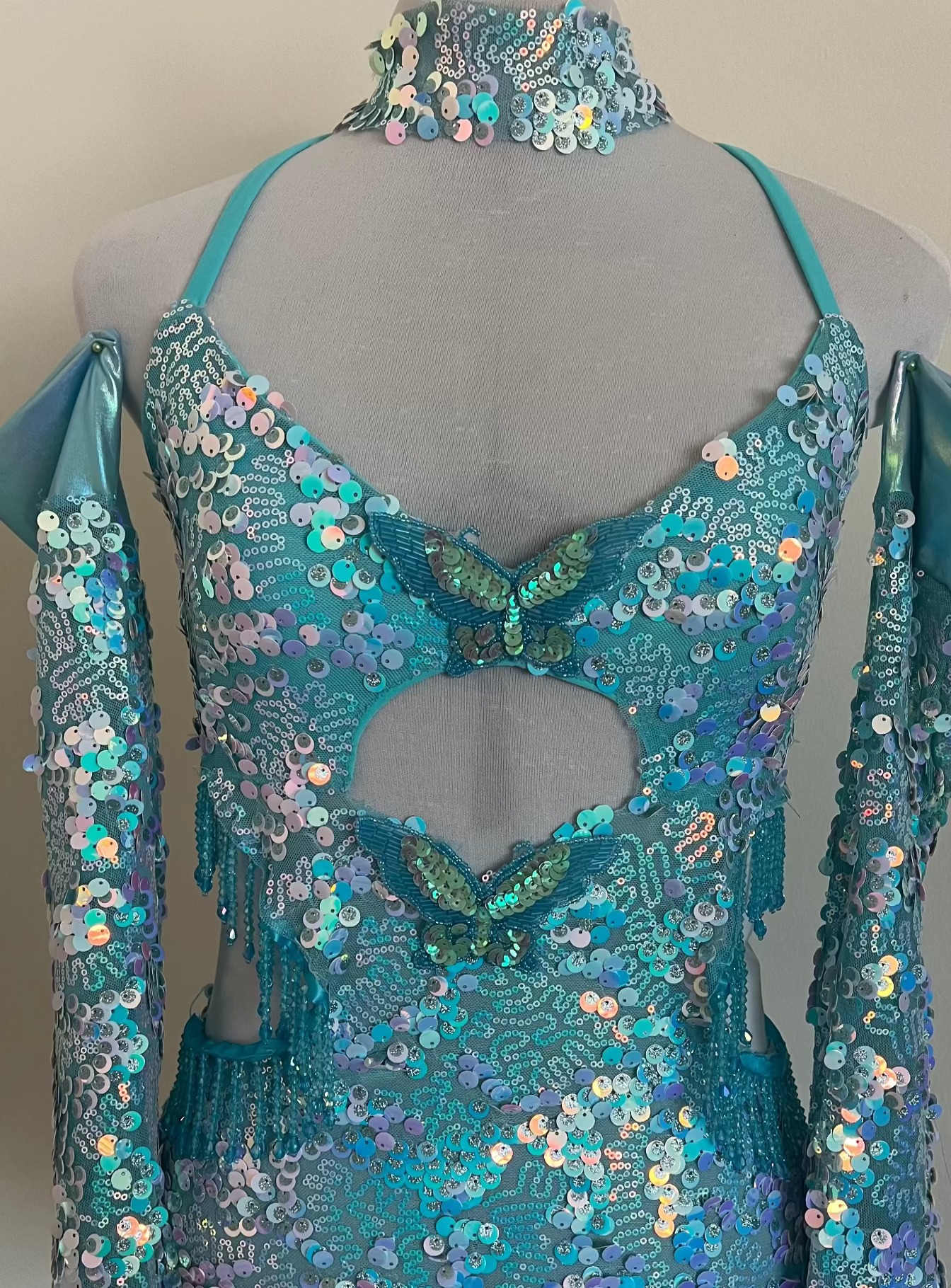 Turquoise sequin dress on a mannequin against a plain background