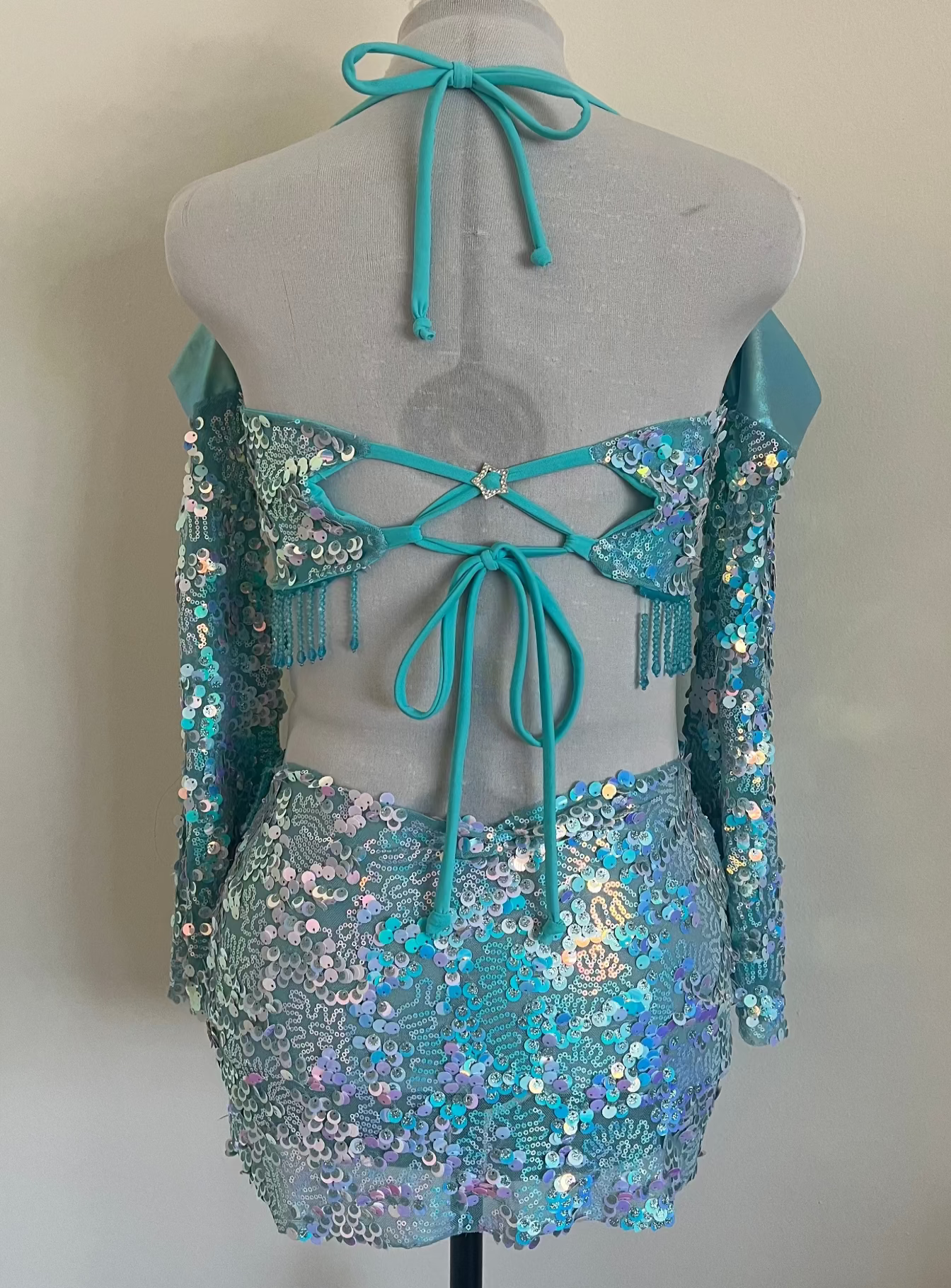 Turquoise sequin outfit on a mannequin against a plain background